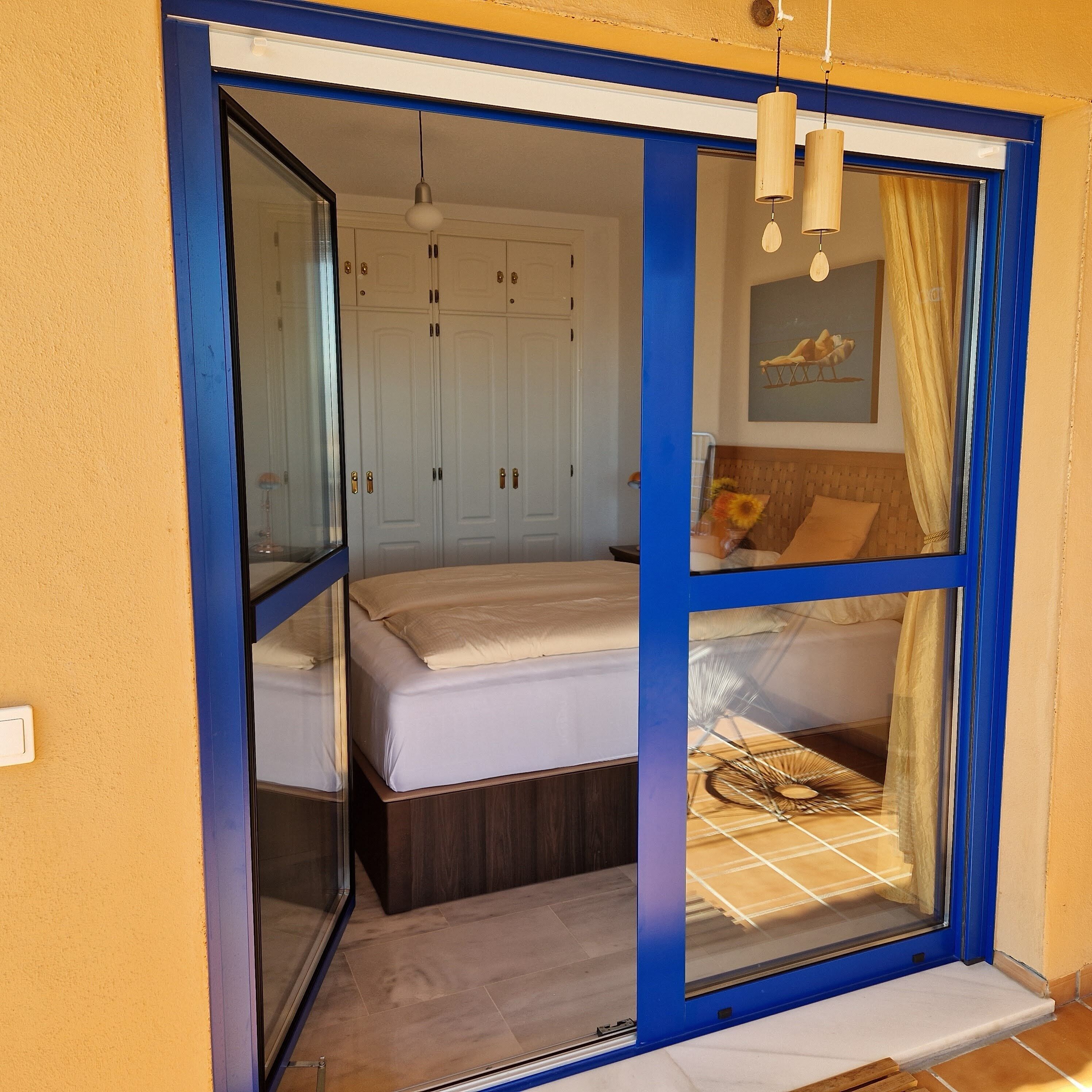 A bedroom with a bed, a wardrobe, and a window with curtains.