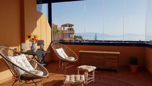 A balcony with wicker chairs, a small table, and a potted plant. - Your vacation home with fantastic south-facing terrace and breathtaking sea view (Manilva)