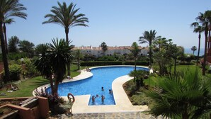 A swimming pool surrounded by palm trees and a well-maintained lawn. - Your vacation home with fantastic south-facing terrace and breathtaking sea view (Manilva)