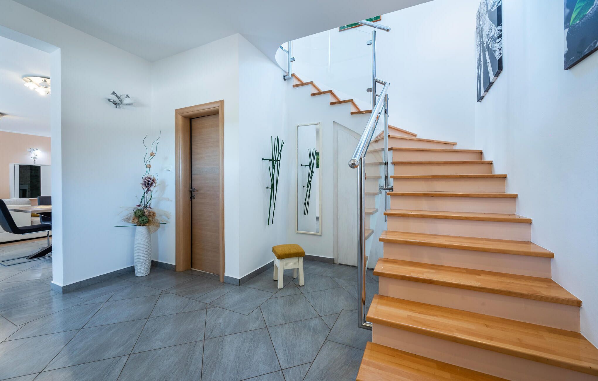 A modern interior with a wooden staircase, a small stool, and a door.