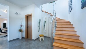 A modern interior with a wooden staircase, a small stool, and a door. - Gorgeous home in Susnjevica (Susnjevica)