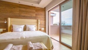 Ein Hotelzimmer mit einem großen Bett, einem Holzkopfende und einer Schiebetür zu einem Balkon.