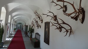 A hallway with a red carpet, arched ceilings, and mounted antler decorations. - Live like a king - maisonette apartment in a castle hotel (Mondsee)