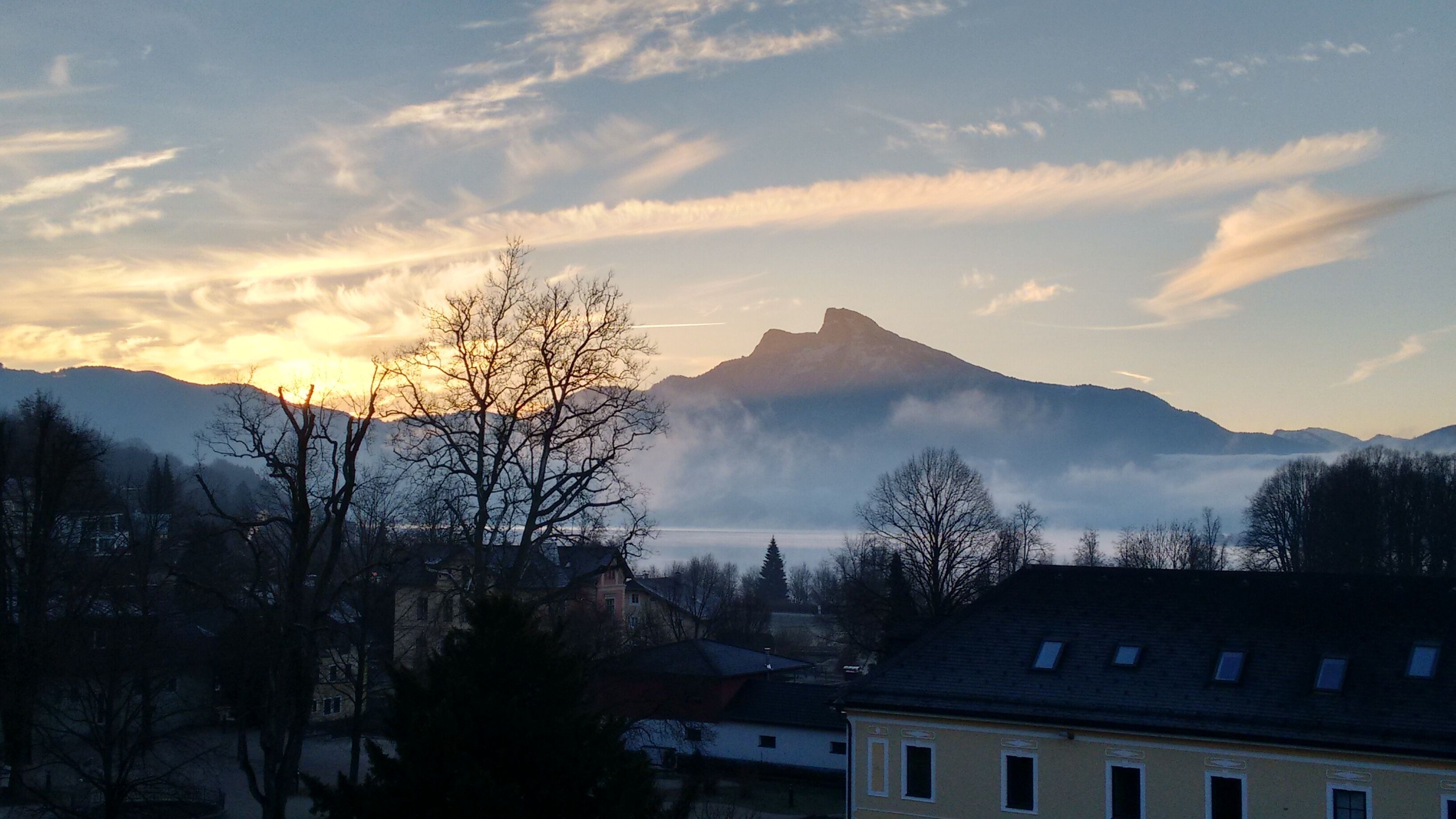 Paisaje montañoso con cielo despejado y un edificio en primer plano.