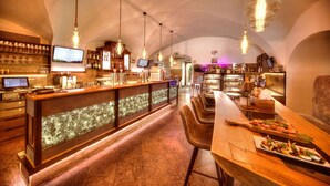 A bar area with a long counter, multiple hanging light fixtures, and a display case with pastries. - Live like a king - maisonette apartment in a castle hotel (Mondsee)