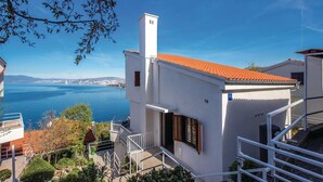 Un edificio costero con fachada blanca, techo de tejas rojas y un balcón con vistas al mar.