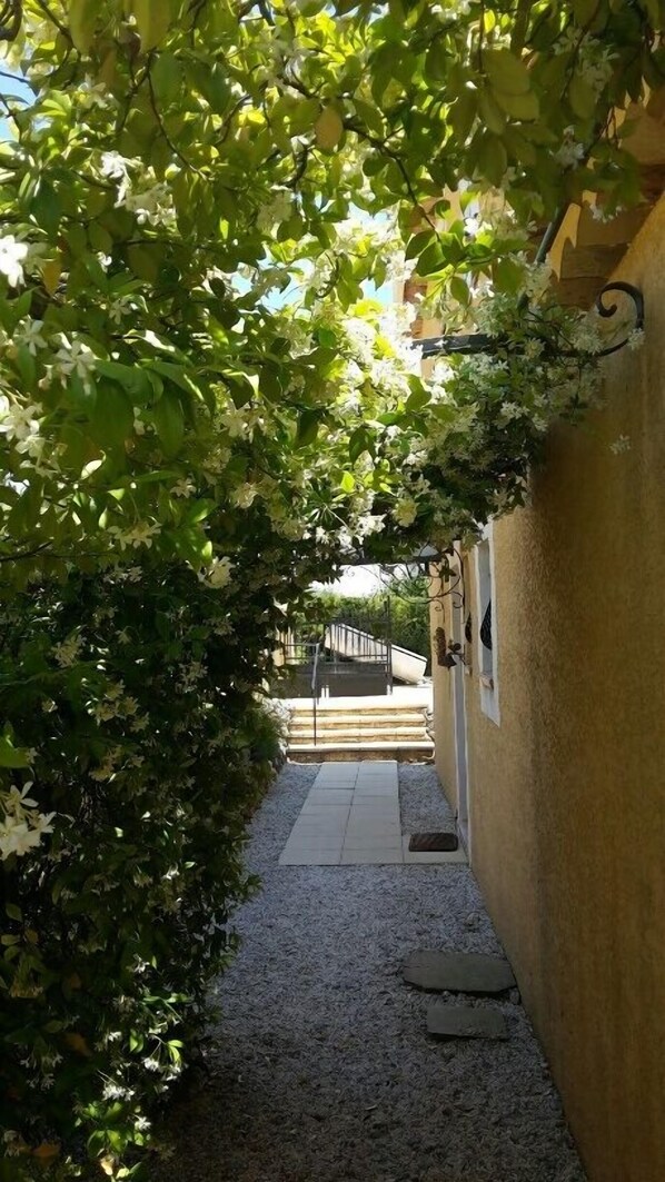 A narrow pathway leading to a building with a yellow exterior. - Apartment in villa with pool, oasis of relaxation, view of mountains (Seillons-Source-D'argens)