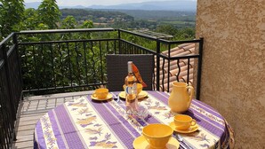 Une table de balcon décorée avec des nappes jaunes et violettes, une bouteille et des bols jaunes.