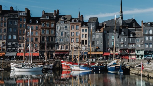 Um porto com vários barcos atracados, cercado por edifícios históricos com estilos arquitetônicos diversos.