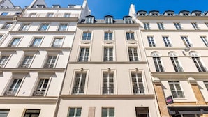 Een rij klassieke gebouwen in Europese stijl, met gelijke architectonische kenmerken, zoals symmetrische gevels, gelijkmatig verdeelde ramen en decoratieve ornamenten.