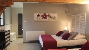 Un dormitorio con cama, mesita de noche, cómoda y un cuadro en la pared.