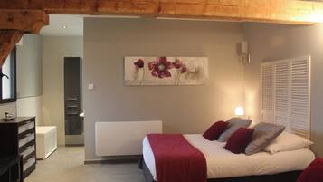 Een slaapkamer met een bed, nachtkastje, dressoir en een schilderij aan de muur.
