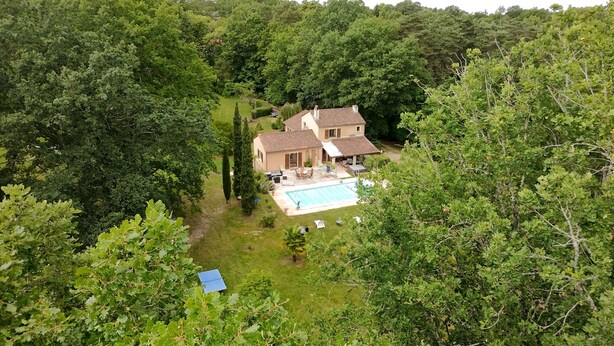 Une maison avec une piscine, entourée d’arbres.