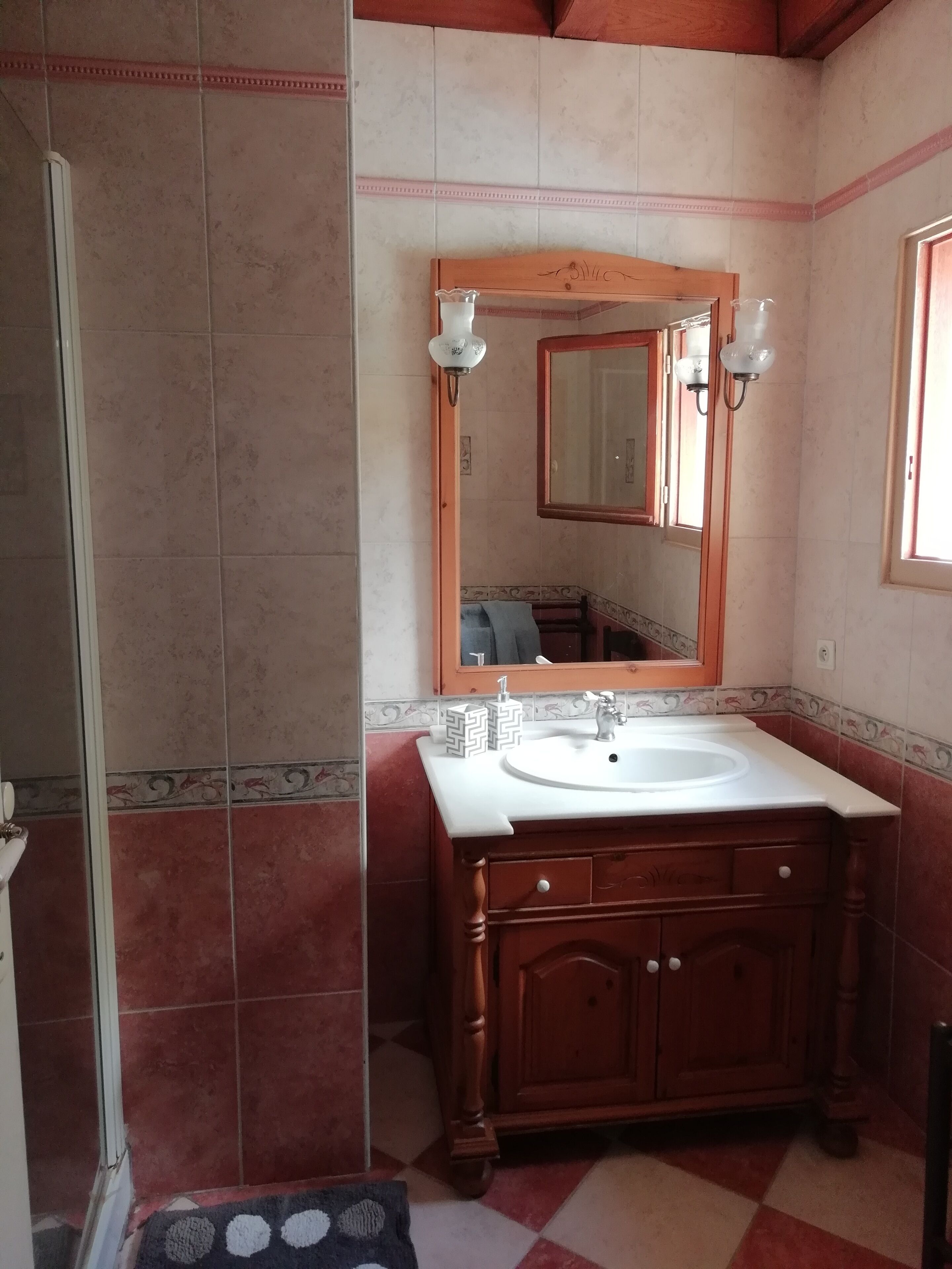 A bathroom with a wooden vanity, a large mirror, and a shower area.