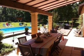 Une terrasse extérieure avec une piscine, un espace salon couvert et une table à manger.