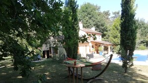 Un hamac sous un arbre, une piscine et une maison avec un jardin.