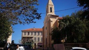 A church with a bell tower, a street with cars, and pedestrians.