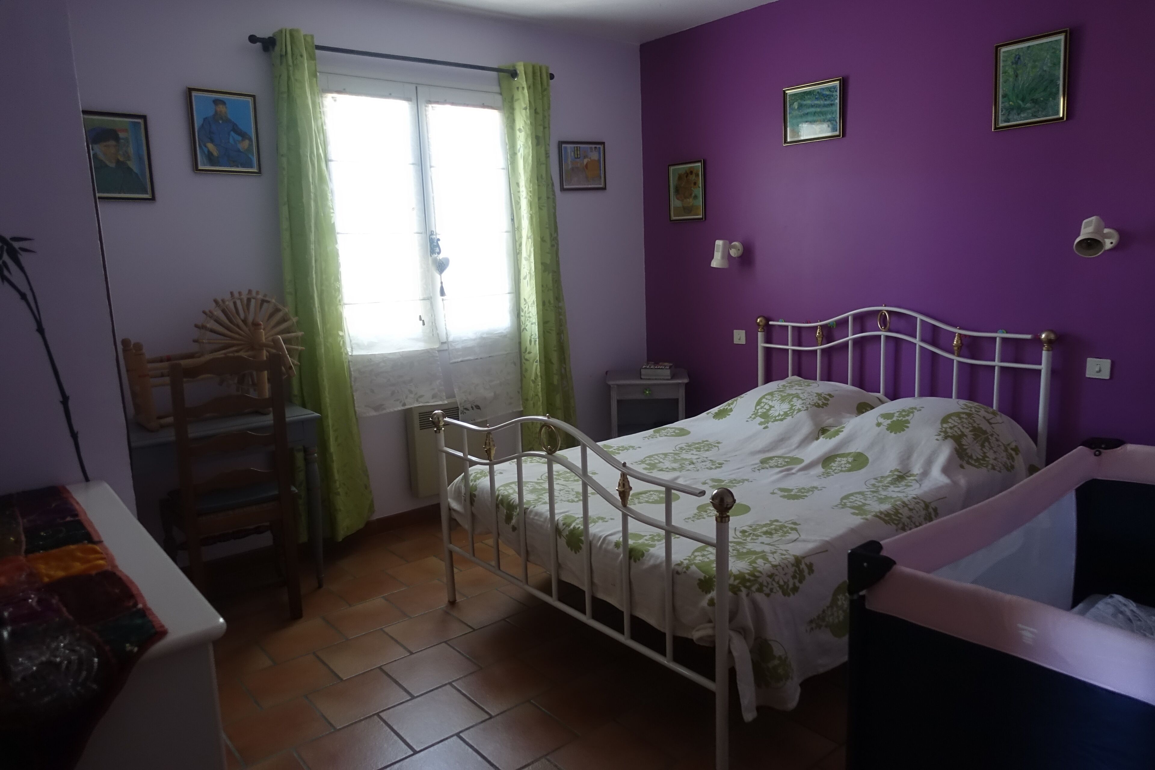 Une chambre à coucher avec un lit, une chaise, une table et une fenêtre avec des rideaux.