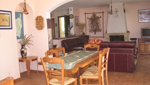 Een eetgedeelte met een houten tafel en stoelen, een bank en een open haard.