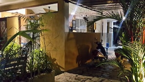 A courtyard with a stone floor, a scooter, and potted plants. - Cycling Hostel Sri Lanka (Unawatuna)