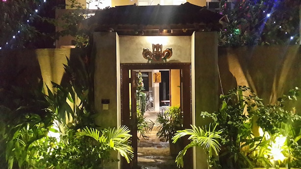 A gated entrance with a decorative archway, surrounded by lush greenery and a small water feature. - Cycling Hostel Sri Lanka (Unawatuna)