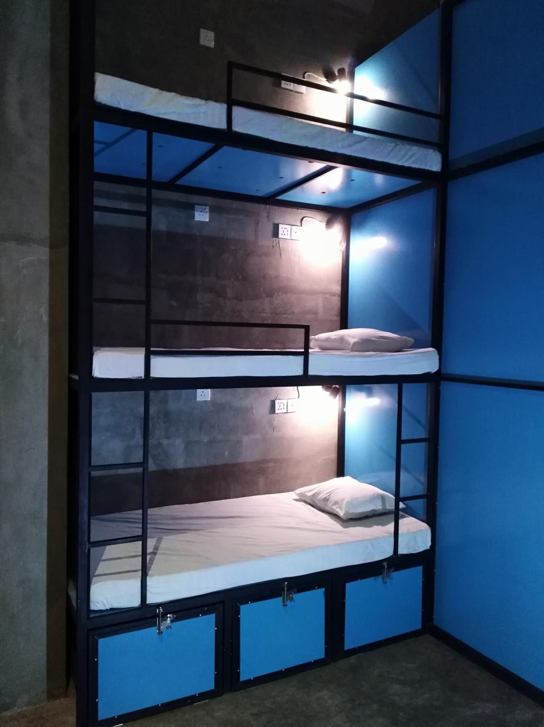 A bunk bed room with three levels, each with a mattress and pillow.
