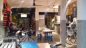 A restaurant with indoor seating, tables, chairs, and bicycles. - Cycling Hostel Sri Lanka (Unawatuna)