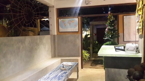 Un espacio interior acogedor con un banco de madera, una mesa pequeña, un mapa del mundo en la pared y un árbol de Navidad.