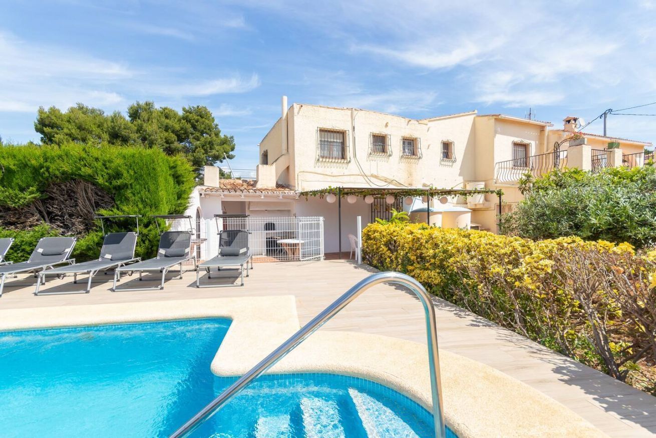 Une piscine avec des chaises longues, un bâtiment blanc doté de balcons et de verdure.
