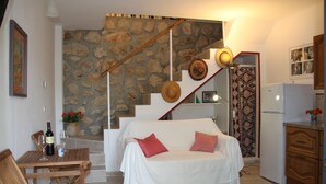 Un espacio acogedor con sofá blanco, mesa de madera y pared de piedra.