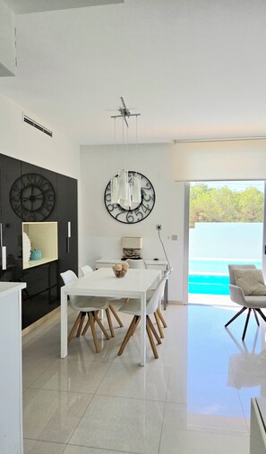 A modern dining area with a white table, chairs, and a ceiling fan. - MODERN VILLA WITH PRIVATE POOL NEAR BEACHES AND GOLF COURSES (Orihuela Costa)