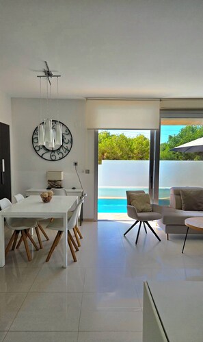 A modern interior with a dining area, a sofa, and a view of a pool. - MODERN VILLA WITH PRIVATE POOL NEAR BEACHES AND GOLF COURSES (Orihuela Costa)