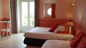 Een hotelkamer met twee bedden, een bureau en een raam met gordijnen.