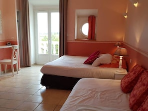 Une chambre d’hôtel avec deux lits, un bureau et une fenêtre avec des rideaux.