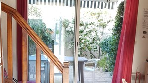 En trappe fører op til en balkon med udsigt over en have og et bord udenfor.