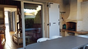 En patio med et bord, stole, en skydedør og en murstensovn.