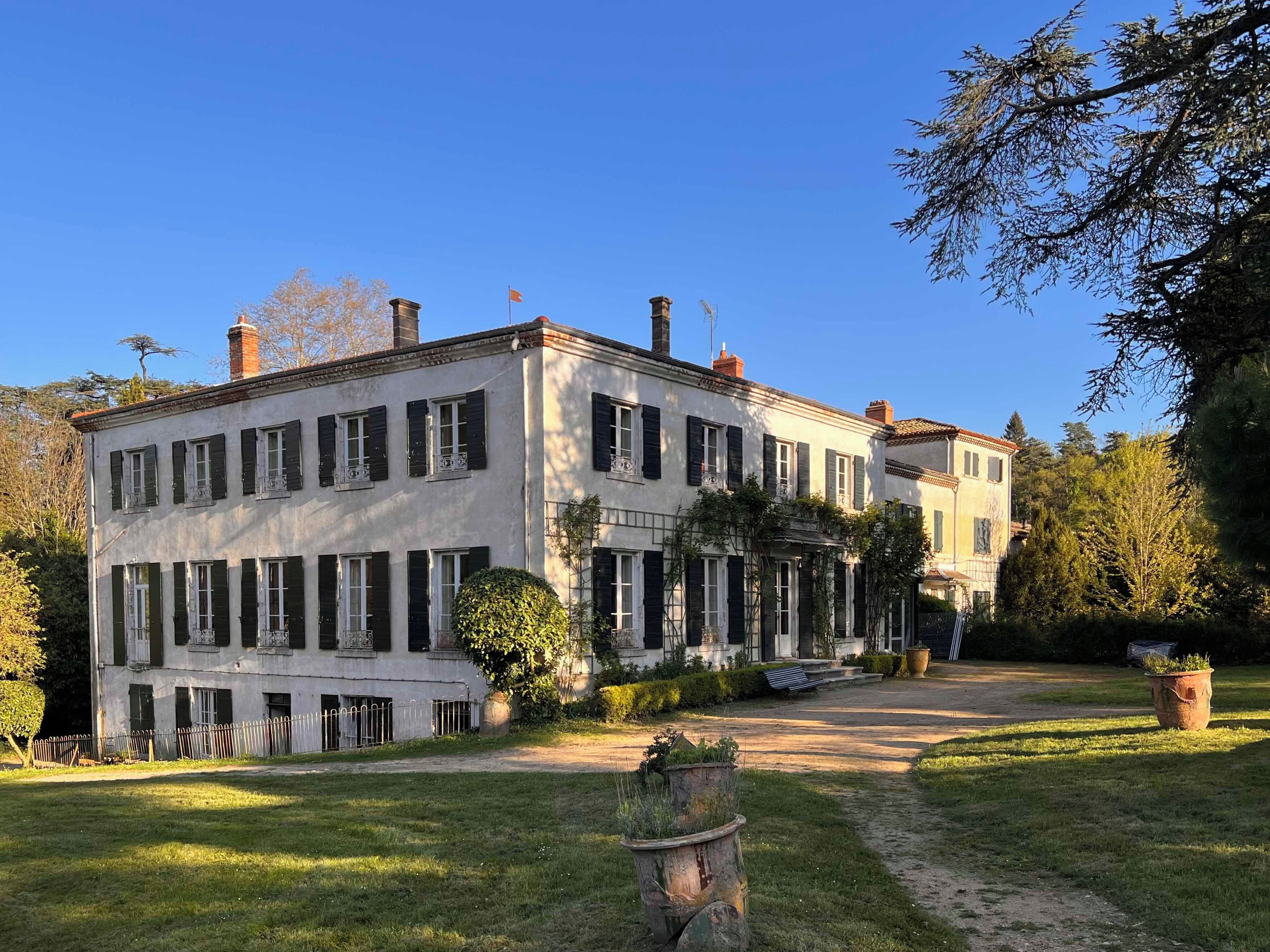 Un bâtiment à deux étages doté d’une façade symétrique, de nombreuses fenêtres avec volets et d’une entrée centrale.
