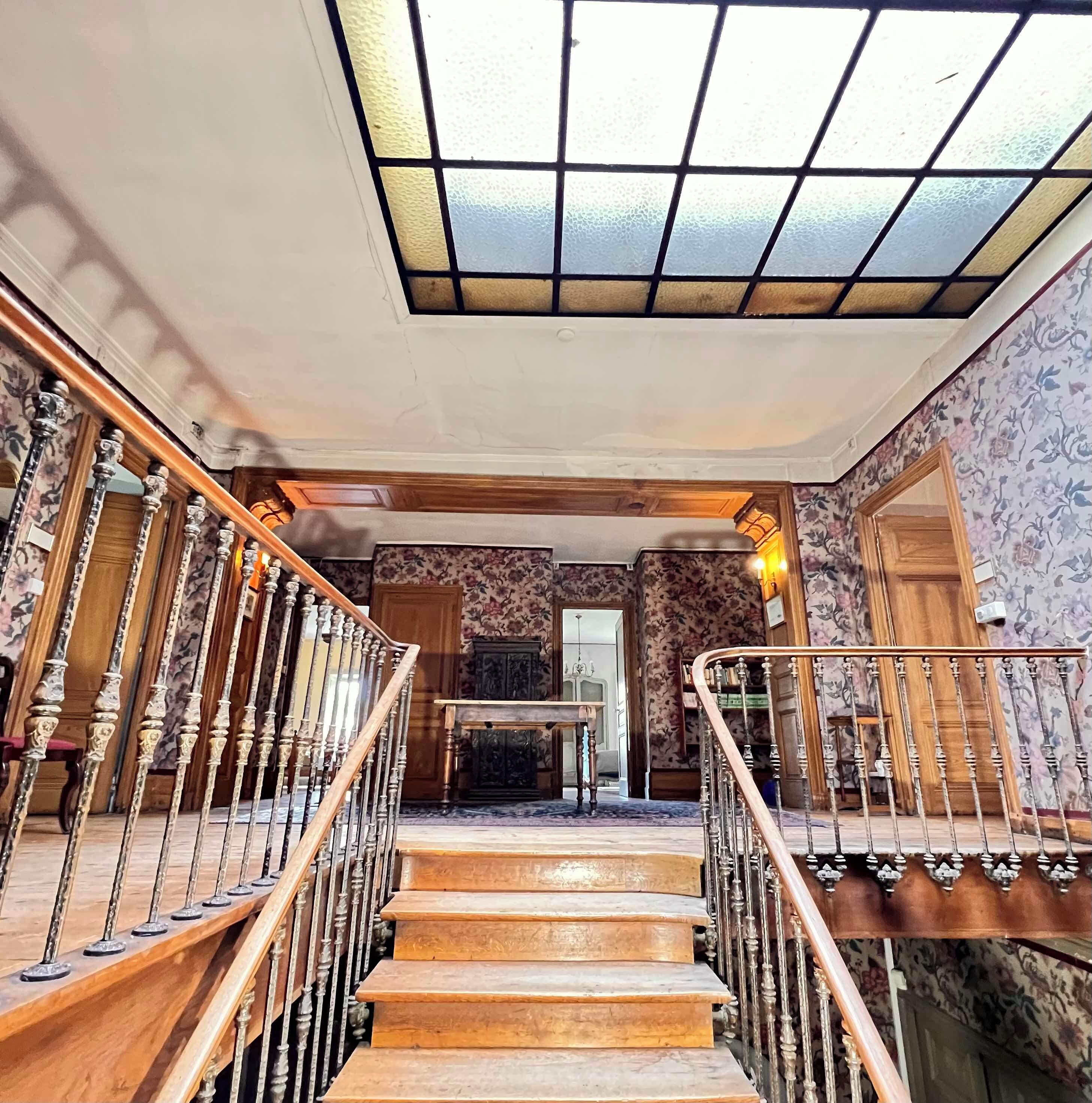Un escalier orné de balustres menant à un palier surmonté d’un lustre.