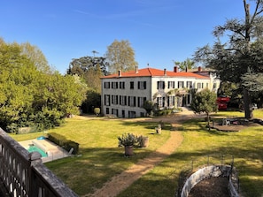 A two-story building with a red roof, surrounded by a well-maintained lawn and trees.