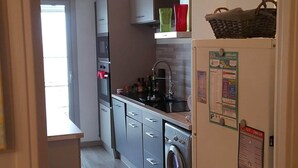 A modern kitchen with stainless steel appliances, a built-in washing machine, and a refrigerator with a calendar. - Apartment F3 of 90 M2 near the sea (Cagnes-Sur-Mer)