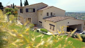 A stone house with a tiled roof, a garage, and a view of the surrounding landscape. - Villa with a breathtaking view, in a quiet countryside,  <br>One week minimum rent  (Saint-Jeannet)