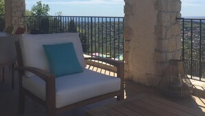 A covered outdoor seating area with a stone wall, a wooden bench, and a white cushioned sofa with a blue pillow. - Villa with a breathtaking view, in a quiet countryside,  <br>One week minimum rent  (Saint-Jeannet)