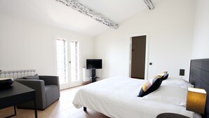 A hotel room with a bed, a desk, a chair, a TV, and a door. - Villa with a breathtaking view, in a quiet countryside,  <br>One week minimum rent  (Saint-Jeannet)
