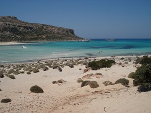 A beach with clear turquoise waters, boats, and rocky terrain. - CRÊTE, beautiful villa with swimming pool and fantastic sea view on souda bay (Kokkinon Chorio, Chania)