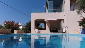 A modern building with a pool, a covered seating area, and a view of the sky.