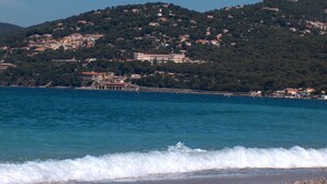 A coastal view with a beach, waves, and a hillside with buildings. - Large villa with a pool - Panoramic view (Îles d'Or and the Giens Peninsula) (Hyères)