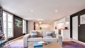 A modern living room with a sofa, a coffee table, and a view into the kitchen.