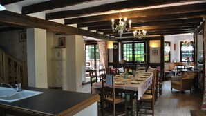 A dining area with a wooden table set for four, surrounded by chairs, and a kitchen area with a sink and cabinets.