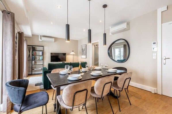 Un espace repas moderne avec une table rectangulaire dressée pour quatre personnes, entourée de chaises rembourrées.