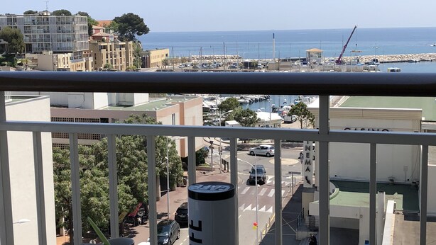 A balcony with a table set for breakfast, a view of the sea, and a café sign. - 180 ° sea view apartment in Carry le Rouet (Carry-Le-Rouet)